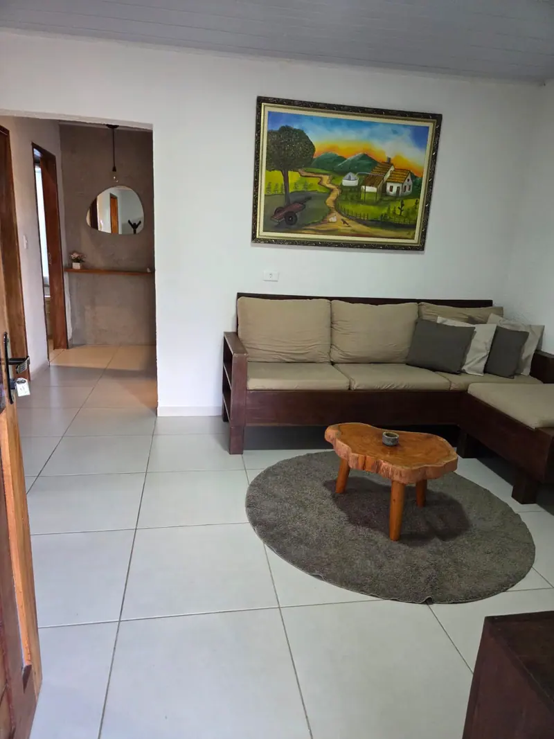 Sala de estar com sofá em L, tapete redondo e mesa de centro de tronco