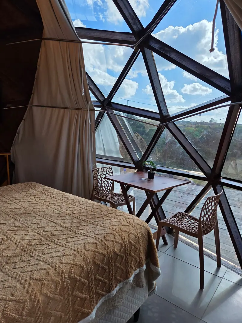 Cama com colcha texturizada diante de janelas triangulares de vidro