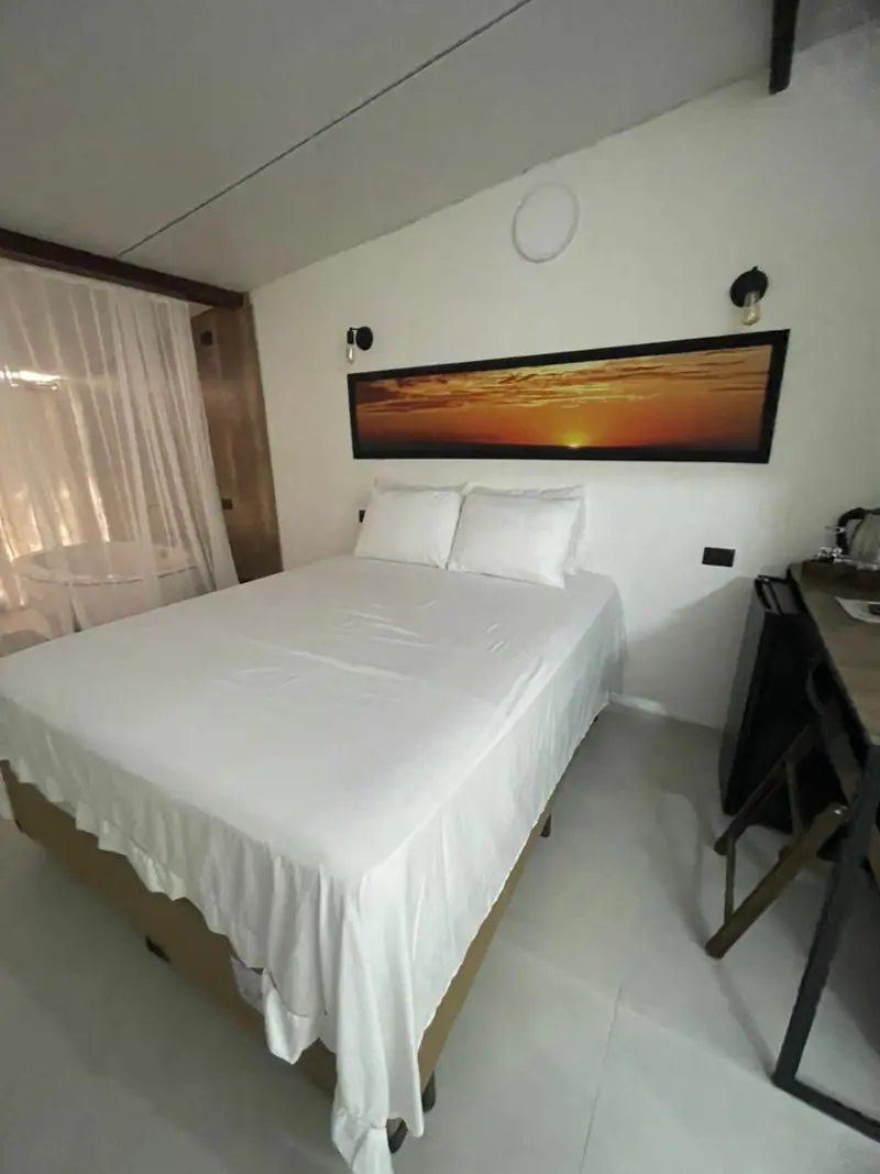 Cama de frente com quadro panorâmico de pôr do sol