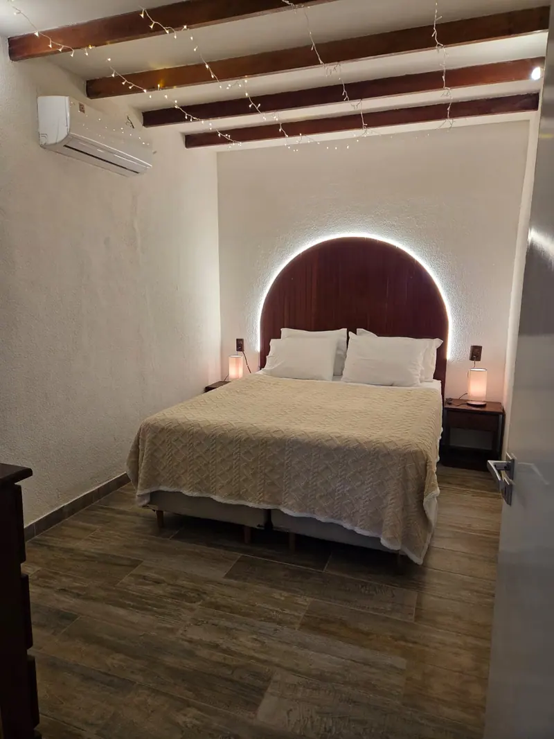 Quarto com cama, cabeceira em arco, ar-condicionado e vigas aparentes