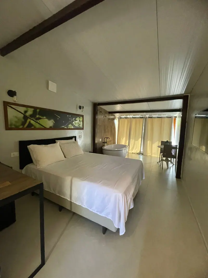 Cama ampla com quadro na parede e banheira ao fundo